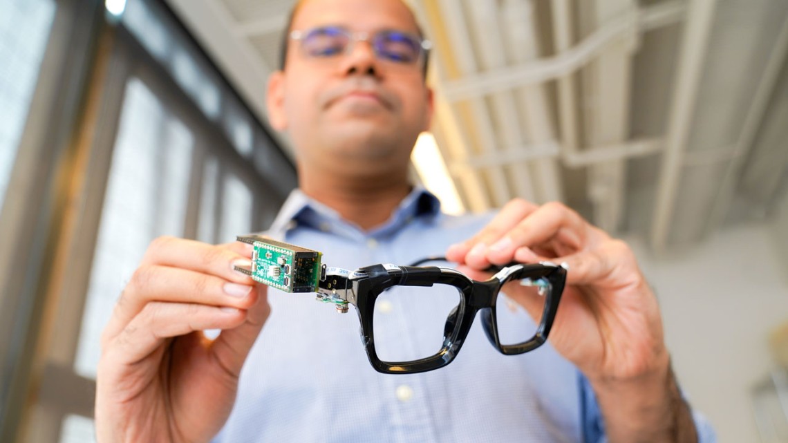 Man in background holding classes with computer chip