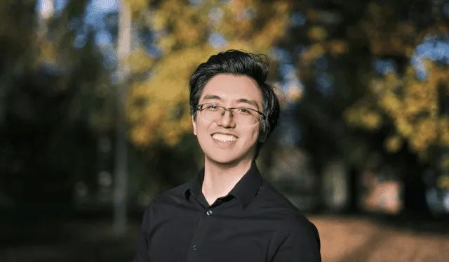 A color photo of a man smiling outside.