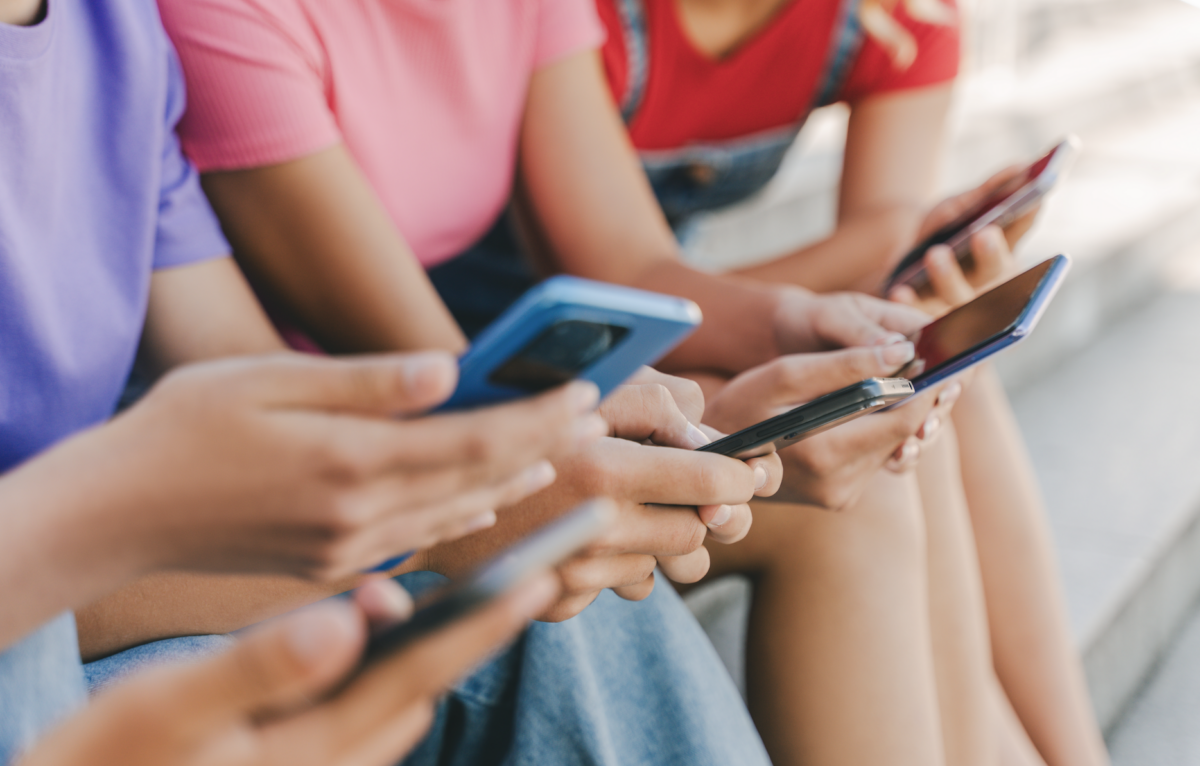 shutterstock_2333643265 kids on social.jpg Kids holding phones
