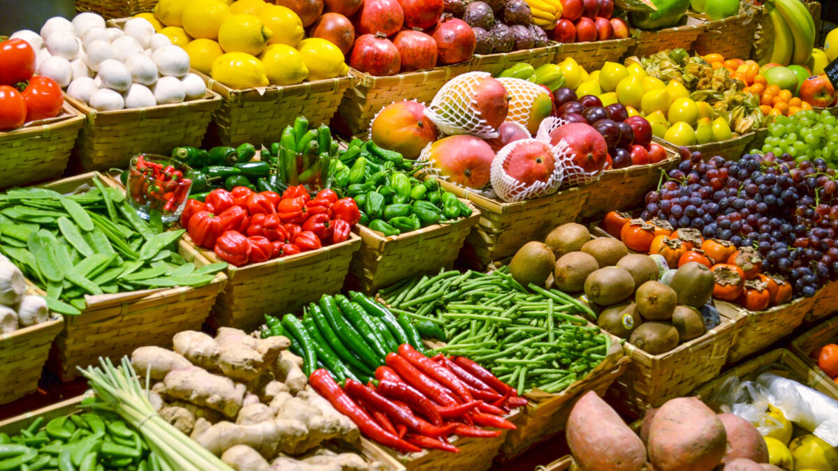 A color photo showing a fruit market with various colorful fresh fruits and vegetables - Shutterstock