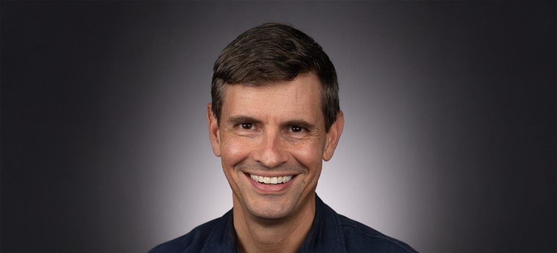 A color photo of a man smiling for a photo.